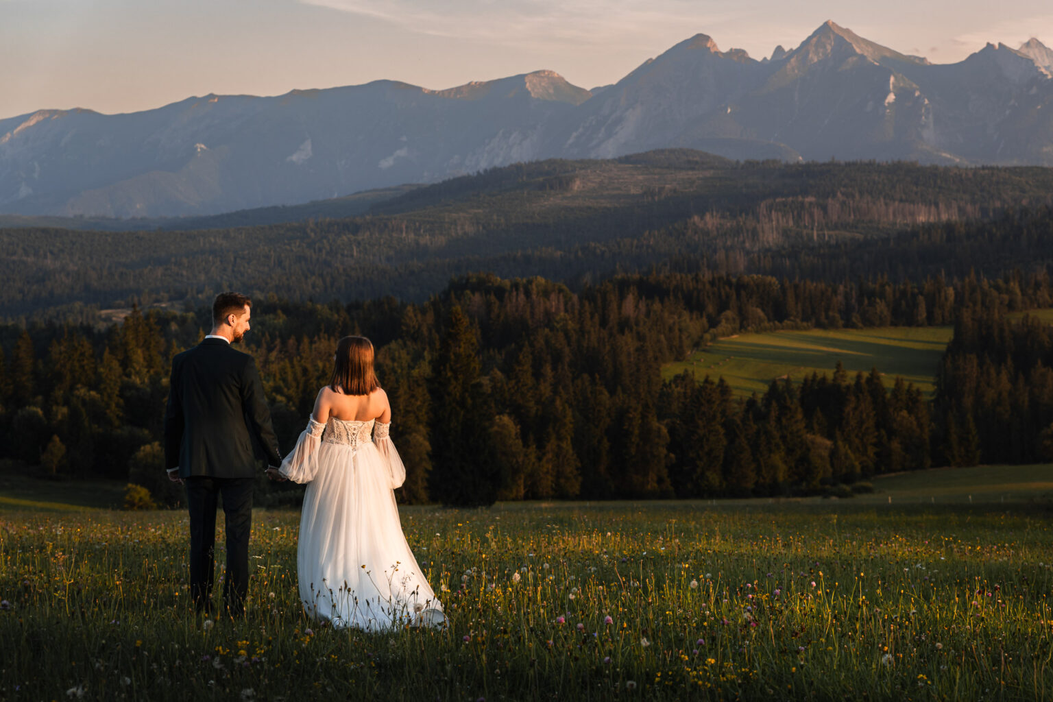 Para młoda idzie przed siebie na tle Tatr